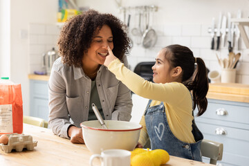 Daughter and Mom being playful whilst cooking in the kitchen