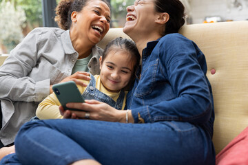 Rainbow family at home having fun and laughing using a smart phone