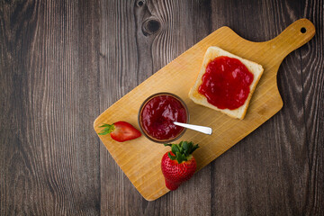 Strawberry jam in the glass jar with fresh berries.