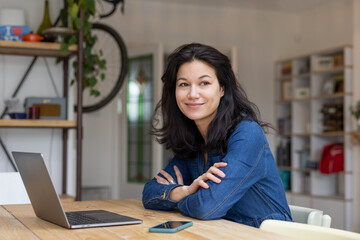 Mid adult asian female working on personal finances using a laptop and a smartphone