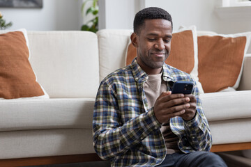 African American male at home using a smartphone and smiling