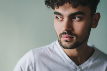 Fototapeta premium Close-up portrait of a serious handsome man looking away standing isolated on studio background. People lifestyle portrait. Closeup portrait. Young male model
