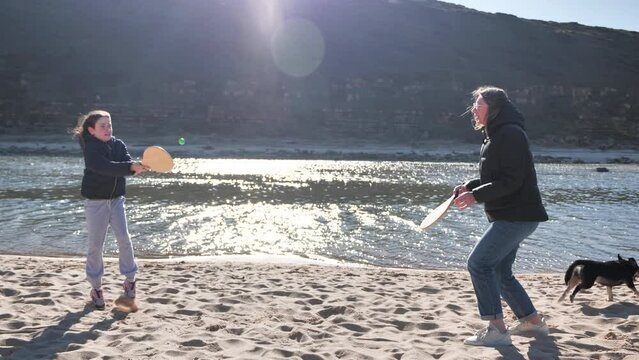 Mother and daughter at the beach playing rackets