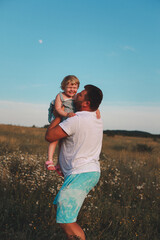 Happy dad and daughter in chamomile field. Portrait of a happy father and daughter in the countryside. Father plays with his daughter. Happy family concept.