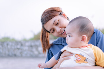 Asian woman holding a baby close up, mother holding baby with love.