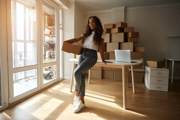 Online store owners use a laptop to prepare parcels of clothing for shipping. Cheerful woman working in the office. Entrepreneur woman doing small e-commerce business