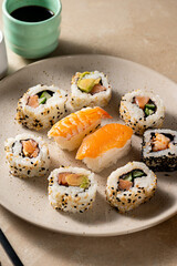 Sushi rolls closeup, with salmon, shrimp, avocado i n a round plate.