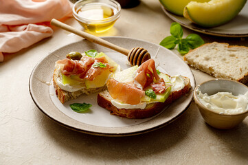 Melon with prosciutto toast with basil and honey. Antipasti snack.