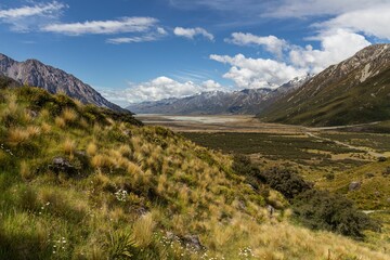 Scenic landscape of a lush green valley surrounded by towering snow-capped mountains
