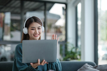 Work at home young asian woman working on laptop computer while sitting and hold coffee cup at home Morning lifestyle concept