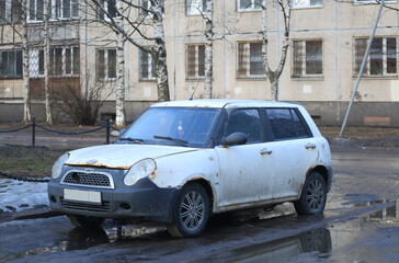 An old white rusty car is parked on the city street, Iskrovsky Prospekt, St. Petersburg, Russia, March 2023