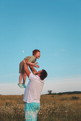 Happy dad and son in chamomile field. Portrait of a happy father and son in the countryside. Happy family concept.