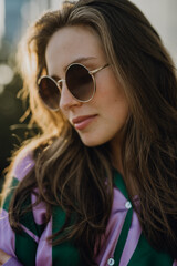 Portrait of beautiful young woman outdoor in city, during sunset.