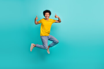 Fototapeta na wymiar Full body portrait of overjoyed carefree man jumping demonstrate thumb up isolated on cyan color background