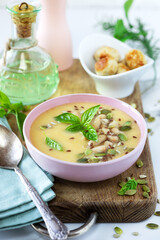Delicious homemade Canellini bean creamy soup served with seeds and leaves of basil in a bowl