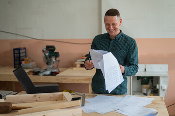 Caucasian man assembles furniture in the workshop and looks at the instructions. 