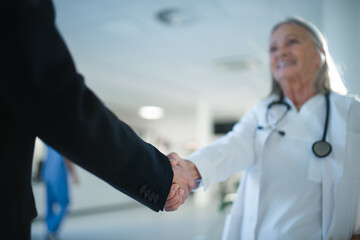 Close-up of handshake of doctor and business woman.