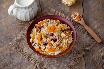 Couscous porridge. Sweet couscous with nuts and dried fruits served in a bowl with jug of milk....