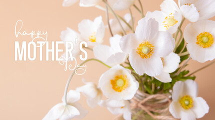 Happy Mothers Day greeting card with close up white anemones flowers on colored background