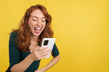 Fototapeta premium Redheaded woman laughing while using the mobile phone