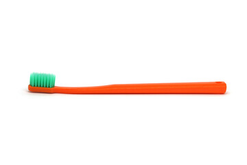 Orange plastic toothbrush with green bristles, white background, side view