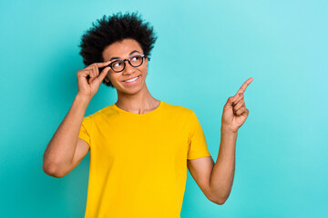 Portrait of toothy beaming smart guy wear yellow t-shirt look directing empty space proposition isolated on vibrant teal color background