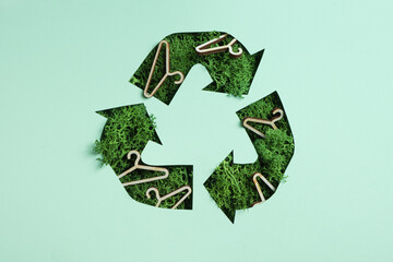 Green moss and coat hangers under paper cut recycling symbol. Save planet recycling cloth concept