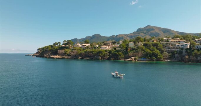 Barco con pescador pesacando con casas de fondo, mediterraneo (Dji Mavic 3 cine)