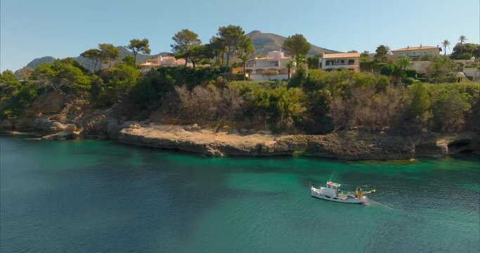 Barco con pescador pescando con casas de fondo, mediterr&aacute;neo (Dji Mavic 3 cine)