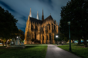 Night panorama of Votiv church (Votivkirche) in Vienna in the park with street lights