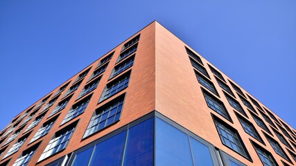 A modern corporate building in the city.  The blue sky is reflected in the buildings large glass windows. Glass facade.