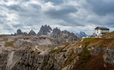 Fototapeta na wymiar Panorama of mountains and hills in Dolomites with mountain hut