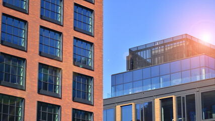 A modern corporate building in the city.  The blue sky is reflected in the buildings large glass windows. Glass facade.