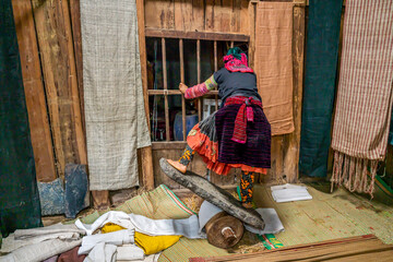 Northern Vietnam, in the village of L&ugrave;ng T&aacute;m a woman flattens in a traditional way  the woven linen.