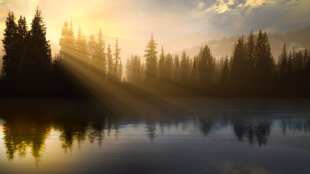 Rays of sunlight and forest reflections in a lake at Sunrise, Utah, USA