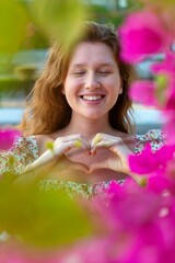 Portrait of happy beautiful girl, young positive woman is smelling beautiful pink flowers in the...