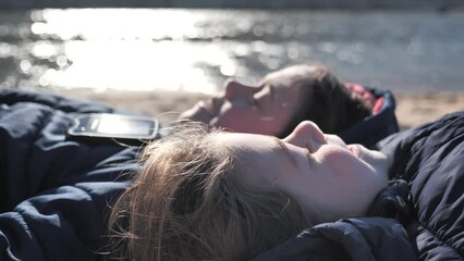Two girls lying down at the beach with closed eyes