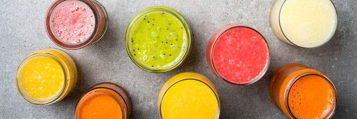 Glasses of fresh juice on gray stone table. Food background