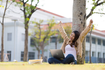 Asian female student Studying for exams in the area of the university. Communicate via mobile phone or laptop connected to the Internet. with many sources of knowledge