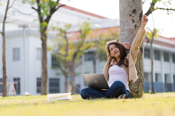 Asian female student Studying for exams in the area of the university. Communicate via mobile phone or laptop connected to the Internet. with many sources of knowledge