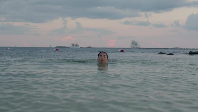 Asian woman swimming in the sea during sunset in Destin, Florida