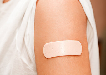 Band aid flesh-colored medical glued on woman shoulder