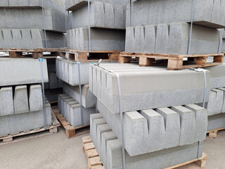 Fototapeta na wymiar Curbs, new blocks for laying stacked in piles on wooden pallets