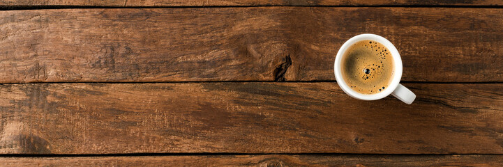 Overhead shot of hot coffee cup on wooden background with copyspace
