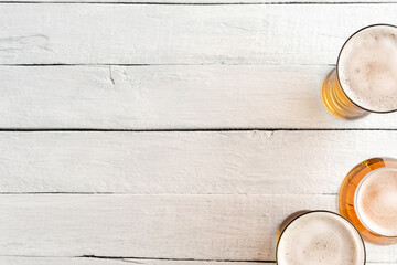 Overhead shot of beer mugs on white wooden background with copyspace