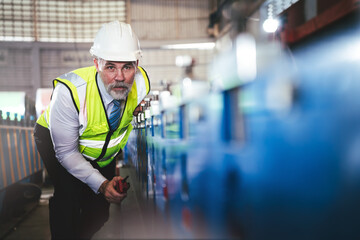Professional senior male engineer industry worker waering safety hard hat checking machanic system in factory, Profession technician engineering inspection in manufacturing warehouse.