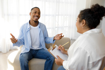 Positive african man smiling and joking while listening to therapist