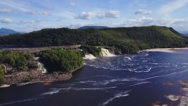 Drone shot over landscape waterfall with meadows in Parque Nacional Canaima, Venezuela with blue sky