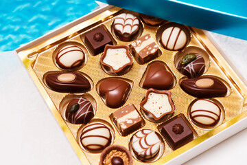 Close up of open small gift box of Swiss chocolate candies. Luxurious selection of milk, dark and white miniature masterpieces