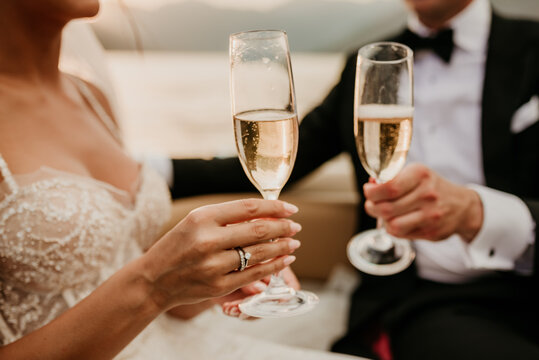 bride and groom newlyweds drinking champagne wine on wedding day sunset wedding dress rings romantic - Powered by Adobe